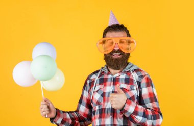 İyi görünüyorsun. Doğum günün kutlu olsun. Erkek bayramı kutlaması. Parti balonlu sakallı adam. Sakallı, traşsız, vahşi adam iş başarısını kutluyor. Saf mutluluğu dile