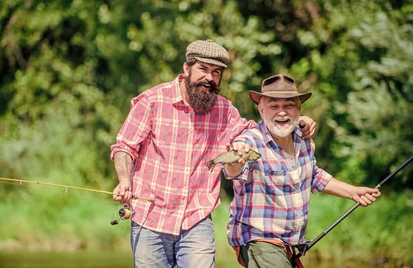 Grande jogo de pesca. amizade. turismo de caça. pesca de pai e filho. dois pescadores felizes com vara de pesca e rede. Acampar na margem do lago. conceito de uma fuga rural. Passatempo. Tempo de pesca da mosca — Fotografia de Stock