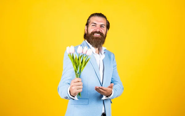 gentleman hold flower bouquet. concept of flower shop. man with beard and stylish hair. holiday and celebration. floral gift for mothers or womens day. happy man with tulip flowers