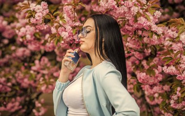 Kiraz çiçeği aroması. Kadın parfümü. Bahar parfümü. Süslü bir tarz. Aromatik bileşikler. Doğal kokulu gerekli yağlar. Eau de Toilette 'de. Şatafatlı bir koku. Modaya uygun bir kadın parfüm şişesi tutuyor.