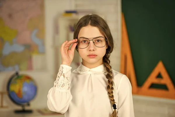 Mirada inteligente. Niña posando en la escuela en la lección. Aprendiendo diferentes temas. de vuelta a la escuela. profesor es una carrera futura. Estudiante de secundaria aprendiendo geometría en clase. geografía hombre en la pared —  Fotos de Stock