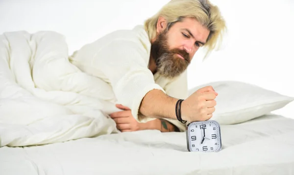 Hate early morning awakening. Sleepy guy and alarm clock in bed. Bearded man with alarm clock. Hipster want to sleep. Schedule. Getting to bed on time. Get up right now. Stressed man alarm clock — Stock Photo, Image