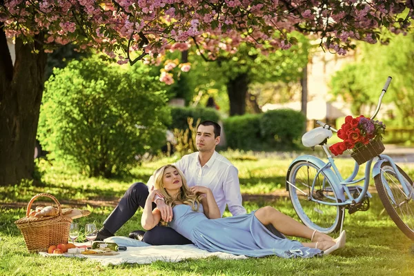 Lovely day. woman and man lying in park and enjoying day together. valentines day picnic. romantic picnic in park. couple date on blanket under sakura flowers. camping. happy couple in love — Stock Photo, Image