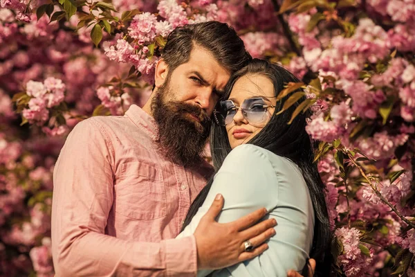 Personas de moda. Temporada romántica. Amor tierno. Un par de sakura fondo del árbol. Todas las flores para ella. Hombre y mujer bonita disfrutando de flor de cerezo rosa. Una cita romántica. Pareja enamorada abrazándose al aire libre — Foto de Stock