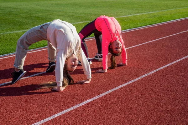 Ginastas meninas flexíveis ficar na posição de caranguejo na pista de atletismo, flexibilidade — Fotografia de Stock