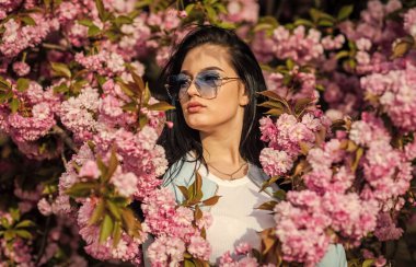 Pembe çiçekli kiraz ağaçları. Seksi kız sakura çiçeğinin tadını çıkarıyor. Kiraz çiçekli kadın. İlkbaharda tatil. Bahar gününün tadını çıkarıyor. 8 Mart. Kiraz çiçekleri. Mutlu kadınlar günü.