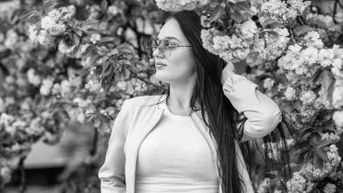 Sakura ona yakışıyor. Muhteşem çiçek ve dişi güzellik. Bahar çiçeğinin açtığı süslü güneş gözlüklü kadın. Cilt için doğal kozmetik. Kiraz çiçekli kız. Sakura ağacı çiçek açıyor. Yumuşak ve yumuşak
