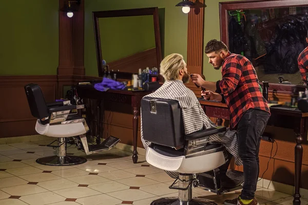 Concept Barbershop. Jeune hipster barbu se coupant les cheveux dans un salon de coiffure. Coiffure professionnelle. Mode de vie. maître coiffeur fait la coiffure et le style avec sèche-cheveux — Photo