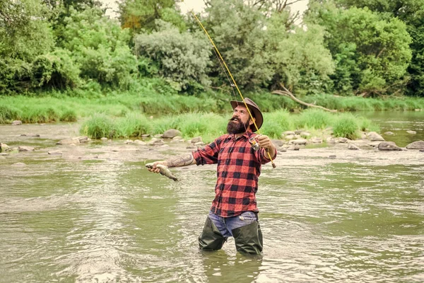 Pasatiempo masculino Fisher. Equipo de pesca Fisher. Pescado en gancho. Hombre brutal usar botas de goma de pie en el agua del río. Pescador satisfecho. La pesca requiere que usted sea consciente y totalmente presente en el momento —  Fotos de Stock