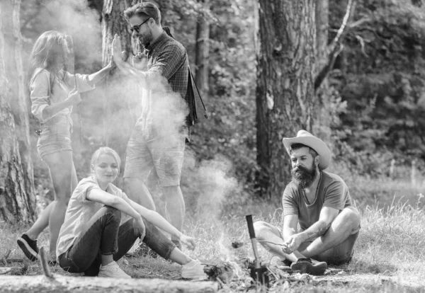 Únete al picnic de verano. Amigos reunión cerca de hoguera para pasar el rato y preparar salchichas asadas bocadillos fondo de la naturaleza. Empresa divirtiéndose mientras asan salchichas en palitos. Reunión para un gran picnic — Foto de Stock