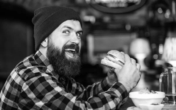 Hipster hungrige Mann essen Burger. Mann mit Bart isst Burger-Menü. Brutale bärtige Hipster sitzen an der Theke. Kalorienreiche Lebensmittel. Mogelpackung. Leckeres Burger-Konzept. Genießen Sie den Geschmack von frischem Burger — Stockfoto