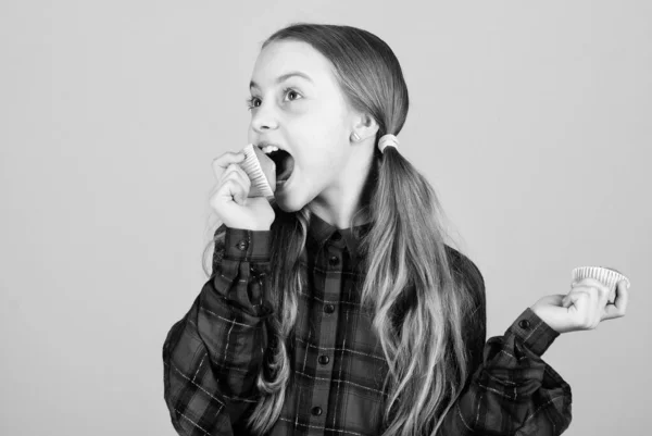 Niña linda niña comiendo magdalenas o magdalenas. Dulce postre. Receta culinaria. Sabroso bocadillo. Los niños adoran las magdalenas. Obsesionado con la comida casera. Alimentación saludable y calorías. Deliciosas magdalenas — Foto de Stock