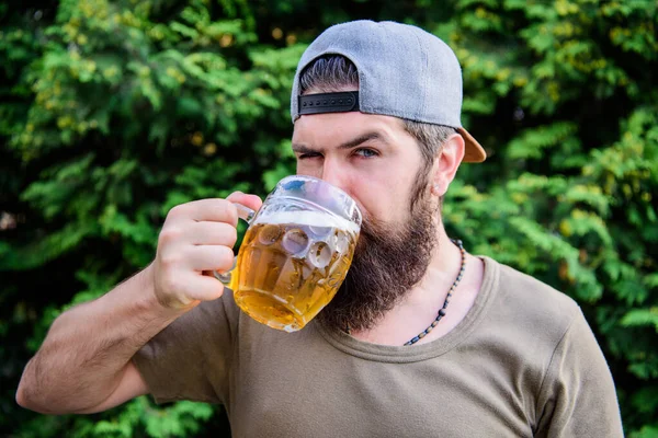 Cieszy się piwem alkoholowym. Brodaty mężczyzna pijący napój alkoholowy latem. Hipster z alkoholem na łonie natury. Pije piwo, nie jest alkoholikiem. — Zdjęcie stockowe