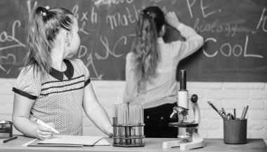 Eğitici deney konsepti. Kız arkadaşlar kimya okuyor. Mikroskop ve test tüpleri masada. Kimyasal reaksiyonlar. Kimya dersi karatahtasında öğrenci. Kimya çalışmasını ilginç hale getir