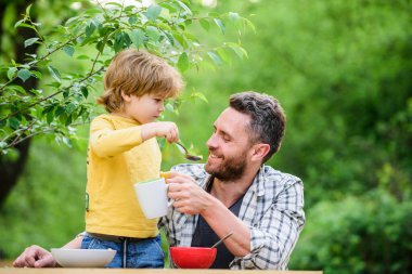 Yaz kahvaltısı. Sağlıklı gıda konsepti. Baba oğul yemek yer ve eğlenir. Bebeği besliyorum. Çocuklar için menü. Aile ev yapımı yemeğin tadını çıkarır. Yemek alışkanlıkları. Babasıyla yemek yiyen küçük bir çocuk.