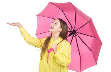 Mutlu stil sahibi kız, beyaz üzerine izole edilmiş yağmur damlasını yakalıyor. Neşeli genç çocuk pembe şemsiyeyi tut.