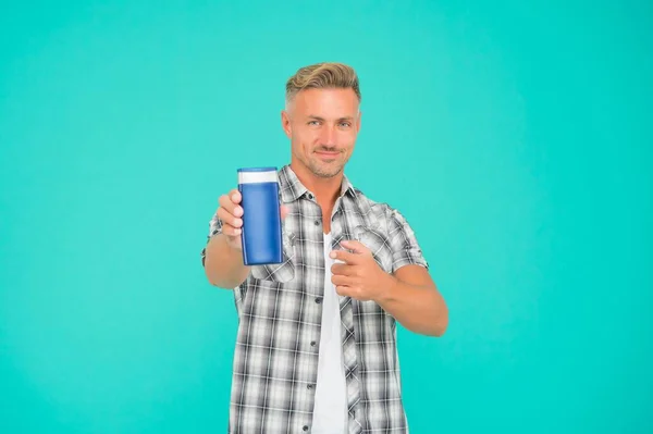 Hombre señala con el dedo el fondo azul de la botella de gel. Gel de baño. Promoción de productos de baño para hombre, espacio de copia. —  Fotos de Stock
