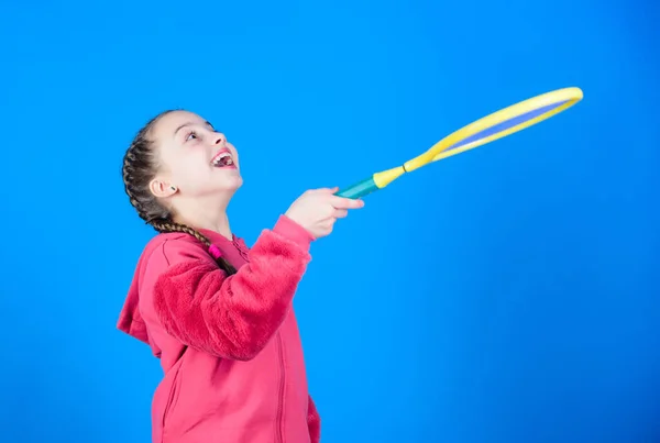 Орієнтований на м'яч. Тенісні види спорту та розваги. Дівчина чарівна дитина грає в теніс. Практикує тенісні навички та розважається. Спортсмен дитячої тенісної ракетки на синьому фоні. Активний відпочинок і хобі — стокове фото