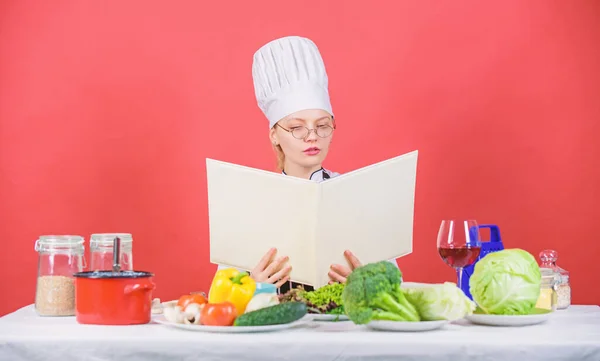 Culinary school concept. Female in hat and apron knows everything about culinary arts. Culinary expert. Woman chef cooking healthy food. Girl read book top best culinary recipes. Traditional cuisine