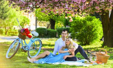 Görünüşte aşk. Sakura çiçeğinin altında rahatla. Birbirine aşık çiftler. Yıldönümü. Yaz parkında mutlu bir aile. Yiyecek ve içecek. Erkek ve kadın. Piknikteki romantik çift. Baharda aşk randevusu