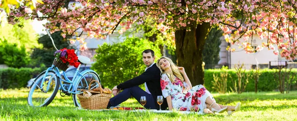 En romantisk historia. mat och dryck. man och kvinna. romantiska par på picknick. Kärleksdejt på våren. Koppla av under blommande sakura. par förälskade. firar årsdagen. lycklig familj i sommarparken — Stockfoto
