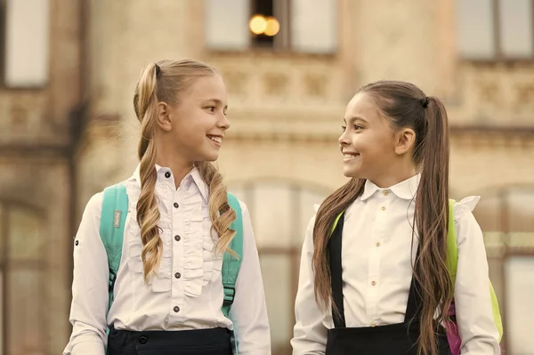 Amigos del alma gemela. Lindas colegialas con largas colas de caballo con aspecto encantador. Fin del año escolar. Alegre colegialas inteligentes. Colegialas felices al aire libre. Pequeñas colegialas usan uniforme escolar — Foto de Stock