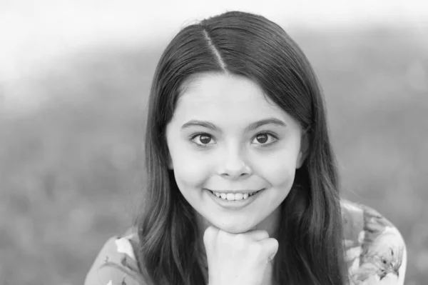 Menina com cabelos longos relaxante no parque ensolarado dia verde grama fundo, conceito sorriso adorável — Fotografia de Stock