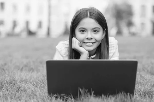 happy kid working on laptop. online education. back to school. teen girl use computer on green grass in park. child with notebook. new technology in modern life. study. Shopping online