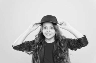 Havalı görünümlü mutlu küçük çocuk sıradan moda tarzında giyiniyor beysbol şapkası takıyor sarı arka plan, güzellik