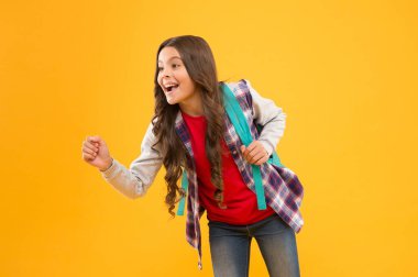 Mutlu bir okul çocuğu elinde bir şey tutuyormuş gibi davran. Sarı arka plan, reklam.