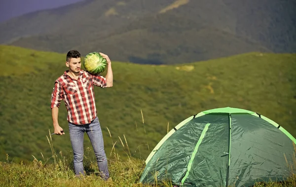 Túrázó és kempingsátor. Az ember görögdinnyét hoz a hegyekbe piknikezni. Nyári szünet. Kellemes kirándulás piknik. Gyümölcs egészséges étel. Kirándulás piknik. Kempingkoncepció. Piknik a hegyekben. Nyári kalandok — Stock Fotó