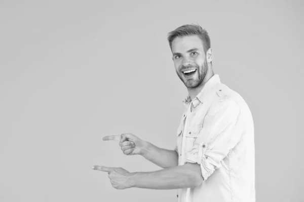 Vrolijke jongen met trendy kapsel presenteren product. Knappe ongeschoren man met haar wijzende vinger. mannelijke zomer casual mode stijl. De gelukkige man heeft verzorgd haar. menselijke emoties. kopieerruimte — Stockfoto