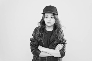 Uzun boylu, esmer, kendine güvenen küçük bir kız çocuğu gündelik moda tarzında giyiniyor. Kollarını çapraz sarı arka plan, kendine güven.