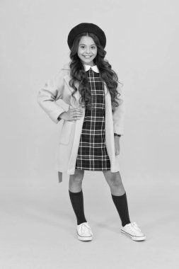 Çok modaya uygun görünüyorsun. Eğitim konsepti. Okul ve moda. Öğrenci üniformalı çocuk. Sarı arka planda Fransız bereli bir çocuk. Şık bir genç üniversite öğrencisi. Okula giden montlu küçük kız.