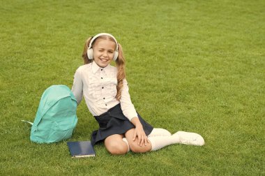 Eğitim güvencedir. Şirin kız müzik dinler. Okul bahçesinde kitabı olan mutlu anaokulu kızı. Okula dönüyorum. Çalışkan çocuk kulaklık takıyor. Eğitim konsepti. çevrimiçi öğrenmenin sıradan günü