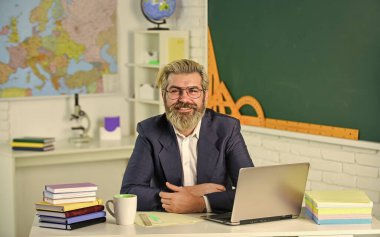 Okul projesi. Erkek işçi okul öğretmeni sınıfta. Yakışıklı hippi olgun eğitimci. Mesafe öğrenme. Yorgun hissediyorum. Kronik yorgunluk sendromu. İlk olarak yıl içinde kaç kredi alınacağını hesapla