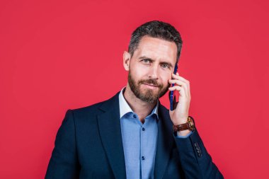 Takım elbiseli olgun bir adam cep telefonuyla konuşuyor, iş görüşmesi.