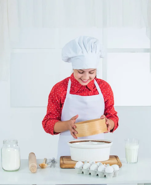 Regarde ce que tu cuisines. heureux adolescent fille cuisson pâte. gamin en uniforme de chef. cuisine et gastronomie. — Photo