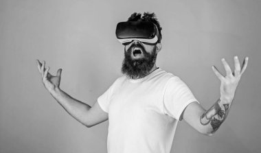 Gözlüklü, yeşil arka planda sakallı bir adam. Güç kavramı. Sanal gerçeklikte etkileşim içindeyken bağıran bir hippi güçlü bir şekilde el kaldırıyor. Kafasına monte edilmiş adam VR ile etkileşim içinde