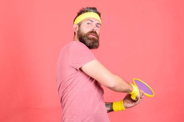 Sakallı hippi adam spor kıyafeti giyer. Eğleniyorum. Tenis aktif eğlence. Tenis oyuncusu modası. Tenis sporu ve eğlence. Hippi atlet elinde tenis raketi tutarken kırmızı arka plan