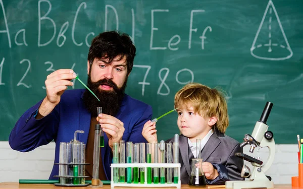 Bärtiger Mann mit kleinem Jungen. Vater und Sohn in der Schule. Labor-Reagenzgläser und Kolben mit farbigen Flüssigkeiten Chemie-Experiment. Laborforschung und -entwicklung. Die Basis fallen lassen — Stockfoto