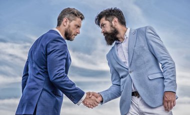 Girişimcilerin tokalaşması başarılı bir anlaşmayı simgeliyor. İş ortağına güvenmen gerektiğine dair bir işaret. Erkekler el sıkışırken mavi gökyüzü arkaplanı. İş anlaşması her iki taraf tarafından da kabul edildi