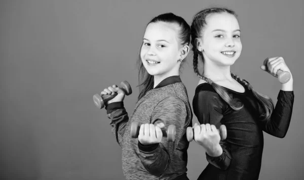 En route pour un corps plus fort. Les filles s'entraînent avec des haltères. Débutant haltères exercices. Une éducation sportive. Les enfants tiennent haltères fond bleu. Sport pour adolescents. Exercices faciles avec haltère — Photo