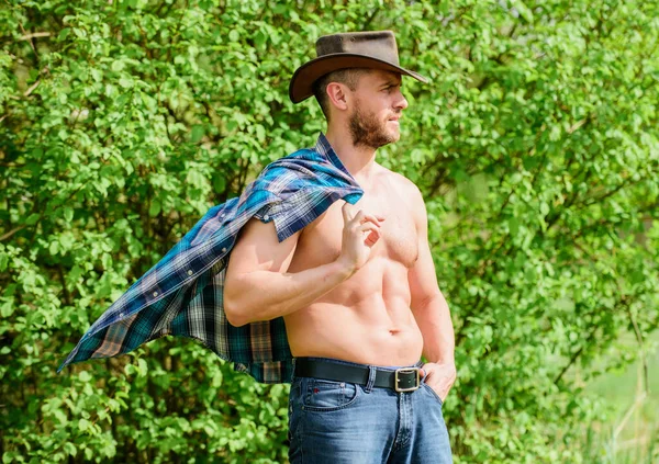 Vaquero fuerte y seguro. Propietario de Rancho. Hombre sin afeitar cara torso muscular vaquero. Concepto de granja. Un vaquero barbudo en la naturaleza. Macho seis paquetes de torso usan ropa de estilo rústico y sombrero de vaquero — Foto de Stock