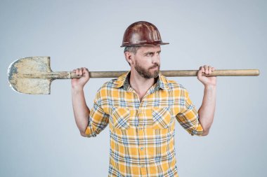 Kask ve kareli gömlek konusunda uzman bir adam inşaat alanında kürekle, işgalle.