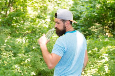 Susuzluk. Günlük su. Vahşi sakallı adam şişe içiyor. Ormanda sakallı olgun bir hippi..