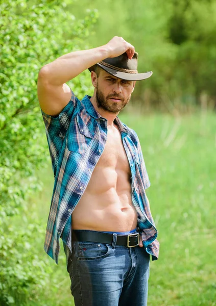 Guy bearded cowboy in nature. Macho six packs torso wear rustic style clothes and cowboy hat. Strong and confident cowboy. Owner of rancho. Man unshaven face muscular torso cowboy. Farm concept — Stock Photo, Image