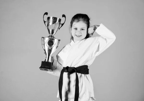 I am the best. knockout. energy and activity for kids. practicing Kung Fu. happy childhood. sport success in single combat. girl with champion cup. martial arts. winner little girl in gi sportswear — Stock Photo, Image