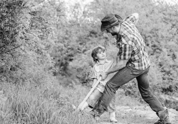 Kisfiú és apa lapáttal, kincseket keresve. Boldog gyerekkort. Kalandvadászat kincsek után. Egy kis segítség a kertben. Aranyos gyerek a természetben, aki cowboyapával szórakozik. Kincsek keresése — Stock Fotó