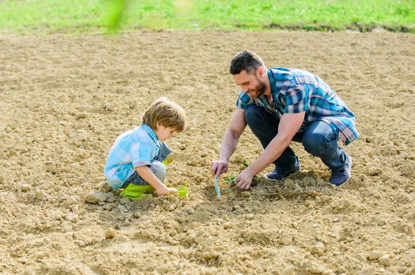 happy earth day. Family tree. father and son planting flowers in ground. small boy child help father in farming. earth day. new life. soils fertilizers. rich natural soil. Eco farm. Caring gardener